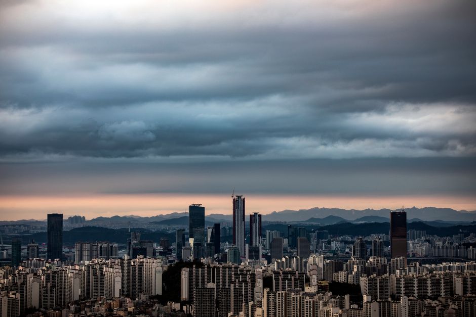 A panoramic view of Seoul's skyline at twilight with dramatic clouds and city lights comin
