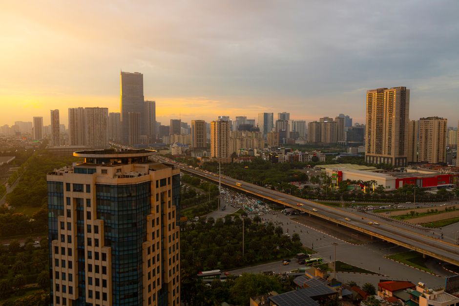 Aerial view of a bustling city at sunset with modern skyscrapers and highways.