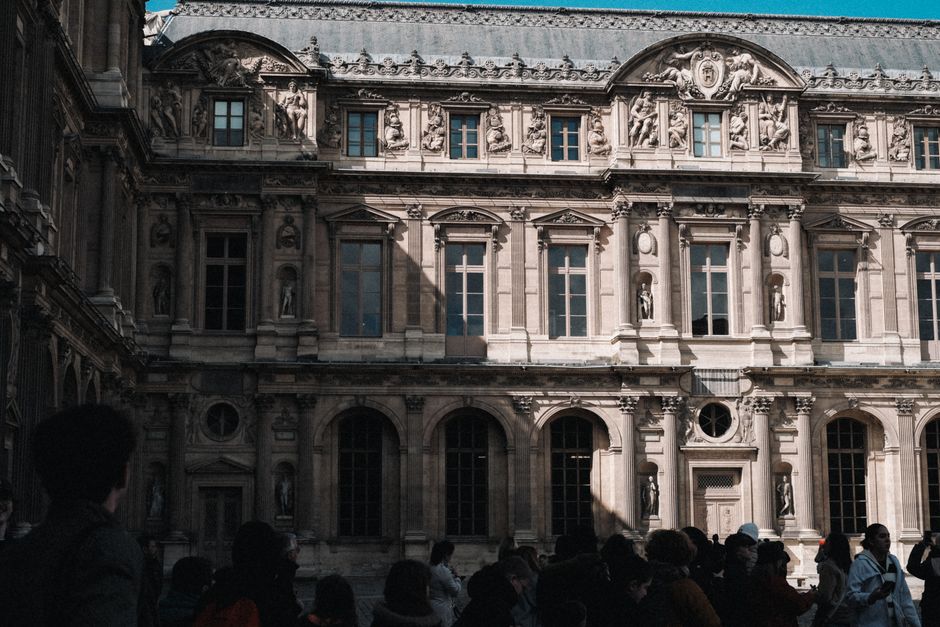 Baroque architecture of the Louvre Museum with a crowd in Paris, France, showcasing stunning facades.