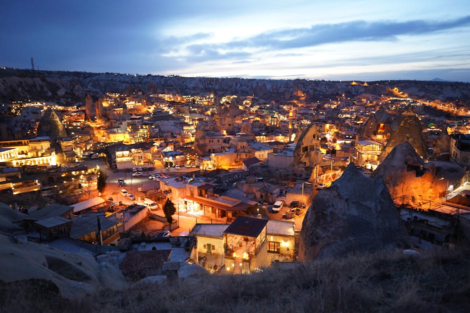 A stunning twilight view of Cappadocia, Turkey, with illuminating lights and unique rock formations.
