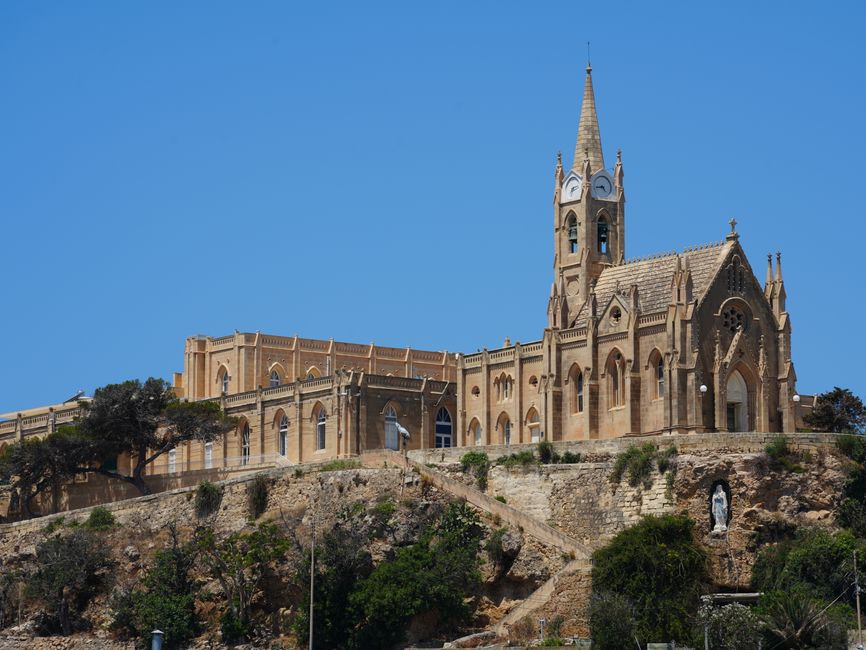 Beautiful exterior view of the Gothic Ta' Pinu Basilica against a clear blue sky in Għarb, Gozo, Malta.