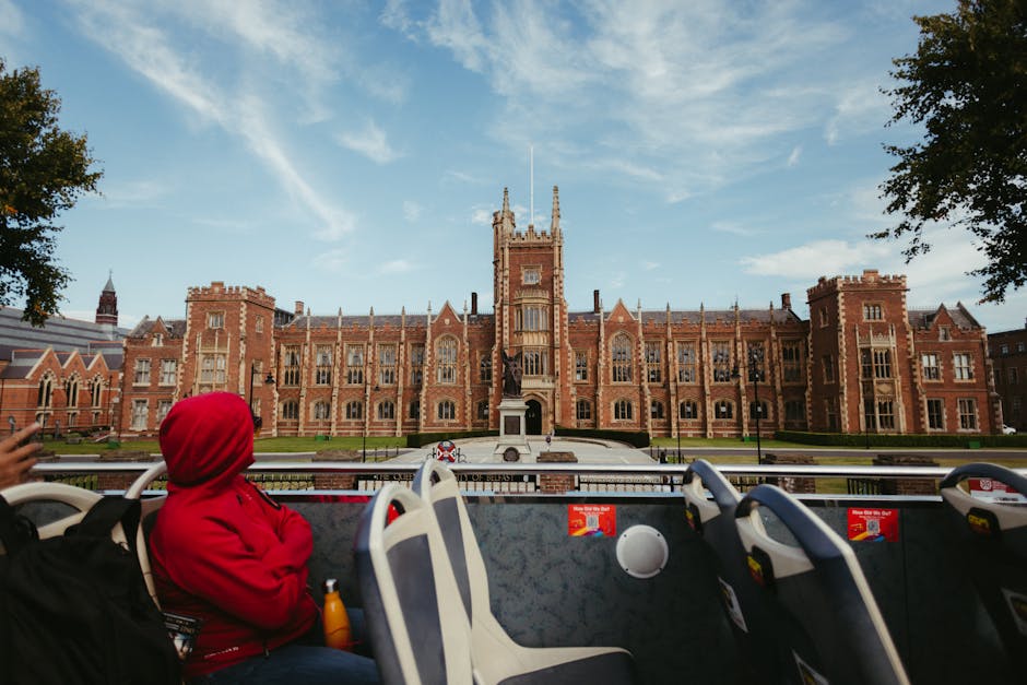 View of Queen's University Belfast captured from a tourist bus, showcasing stunning Gothic architecture and vibrant campus life.