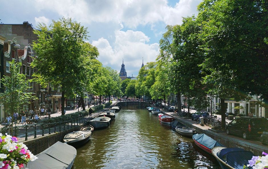 Beautiful summer day on an Amsterdam canal with boats and vibrant greenery.