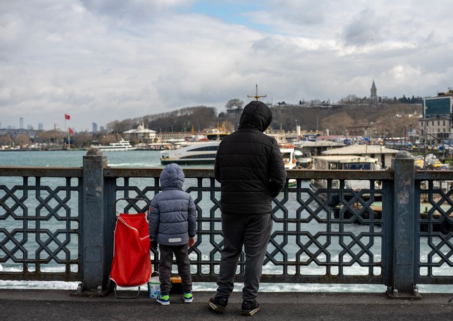 Father and child enjoying scenic winter view of Istanbul from Galata Bridge.