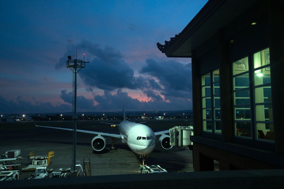 Contemporary aircraft located near airbridge on modern airport airfield against scenic dusk sky