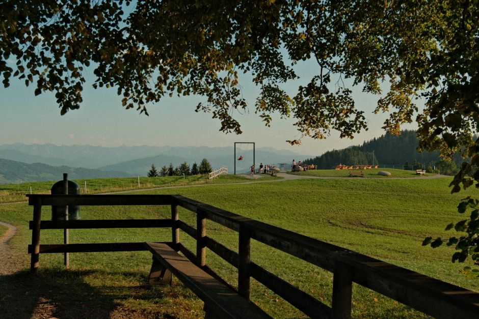 Peaceful park scene with distant mountains and people on swings. Perfect for travel and na