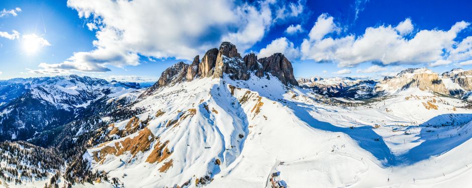 A breathtaking panoramic view of a snow-covered mountain range under a bright blue sky.