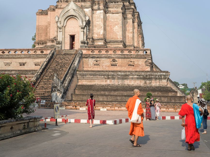 Monks and tourists at Wat Chedi Luang, a historic temple in Chiang Mai, Thailand.